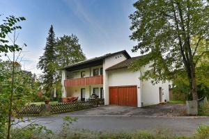 een groot wit huis met een rode garage bij Ferienwohnung Landhaus Helga unterm Schloss in Schwangau