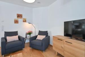 uma sala de estar com 2 cadeiras e uma televisão de ecrã plano em Ferienwohnung Mibba din em Schwangau