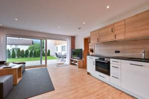 a kitchen with white cabinets and a living room at Monusse Boid Wohnung 6 in Pfronten