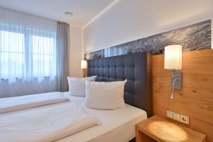 ein Hotelzimmer mit einem Bett mit weißen Kissen in der Unterkunft Landhaus am See Appartement LH 1 in Schwangau