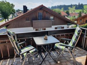 a table and chairs on a balcony with a house at Ferienwohnung Forggensee in Roßhaupten