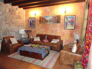 a living room with leather furniture and a stone wall at Cissus Hotel Boutique in Antigua Guatemala