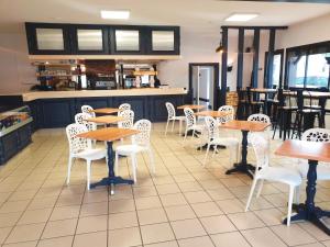 a restaurant with wooden tables and white chairs at Coliwork Le Saint Romain in Dangé