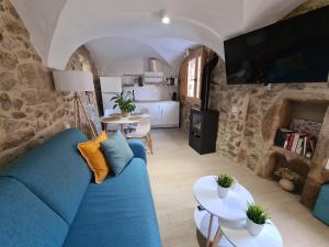 sala de estar con sofá azul y cocina en El Edén Casas Rurales con Piscina y Jacuzzi, en Montánchez