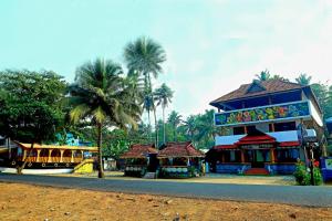 a group of buildings with palm trees next to a street at Relax Beach Inn in Cherai Beach