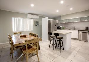 Il comprend une cuisine et une salle à manger avec une table et des chaises en bois. dans l'établissement 3 Seacrets at Shelly, à Urangan