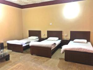 Zimmer mit 3 Betten in einem Zimmer in der Unterkunft Babar House in Faisalabad