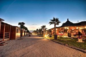 a street with buildings and palm trees at night at Bungalows Park Albufera in El Saler