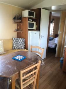 a kitchen and dining room with a table and chairs at Mobilhome (29) 4 pers St Martin aux Buneaux in Saint-Martin-aux-Buneaux