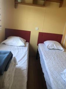 two beds in a room with white sheets at Mobilhome (29) 4 pers St Martin aux Buneaux in Saint-Martin-aux-Buneaux