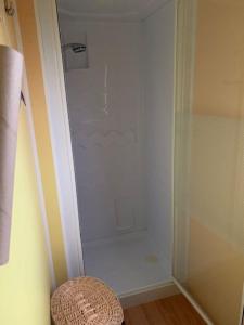 a white shower in a bathroom with a stool at Mobilhome (29) 4 pers St Martin aux Buneaux in Saint-Martin-aux-Buneaux