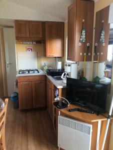 a kitchen with wooden cabinets and a computer monitor on a desk at Mobilhome (29) 4 pers St Martin aux Buneaux in Saint-Martin-aux-Buneaux