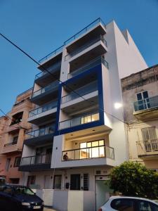 a tall white building with a balcony at Caribbean Cocktail in Marsaskala