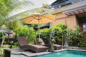 een parasol en stoelen naast een zwembad bij Mancur Guesthouse in Ubud
