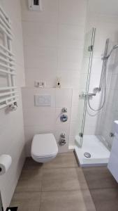 La salle de bains blanche est pourvue d'une douche et de toilettes. dans l'établissement Ferienpark F13-005 Ferienpark, à Heiligenhafen