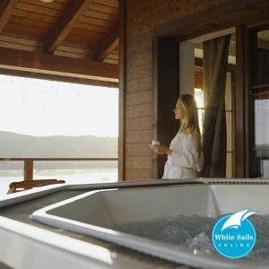 a woman standing in a bath tub with a cup of coffee at White Sails Solina in Solina
