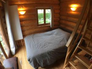 een bed in een houten kamer met een raam bij L'ermitage des vallons in Sulniac