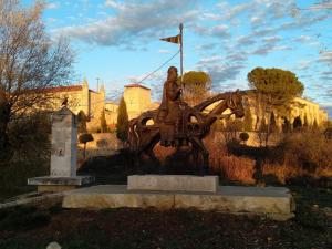 una estatua de un hombre montando un caballo delante de un edificio en La Casa del Obispo, en Caleruega