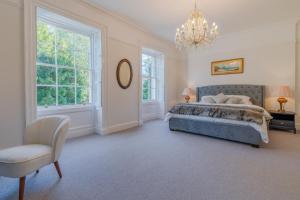 a bedroom with a bed and a chair and a chandelier at Leonard Stanley House in Stonehouse