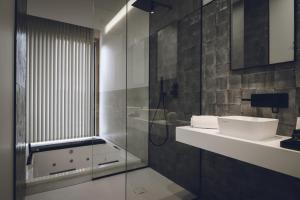 uma casa de banho com uma cabina de duche em vidro e um lavatório. em Atmos Hotel Boutique em Outes