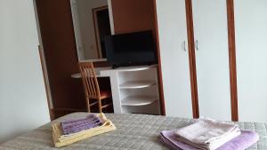 een kamer met een tafel met een televisie en handdoeken bij Rooms Neda in Rab