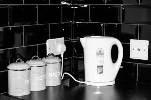 Un mostrador con tres latas de café y una tostadora en Cosy 2 bed flat near train station Basingstoke with FREE Parking!, en Basingstoke