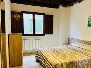 1 dormitorio con cama y ventana en Apartamentos Raíces, en Mogarraz