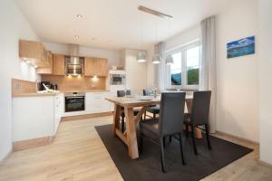 cocina y comedor con mesa de madera y sillas en Landhaus am See Appartement LH 03, en Schwangau