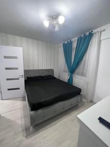 a bedroom with a bed and a blue curtain at Apartament Craiova Magnolia in Craiova