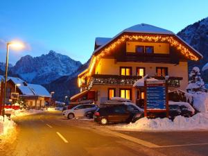 a snow covered building with cars parked in front of it at Apartments Rozle in Kranjska Gora