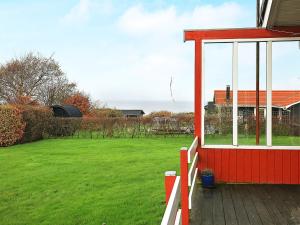 a red house with a white fence and a yard at 6 person holiday home in Vinderup in Vinderup