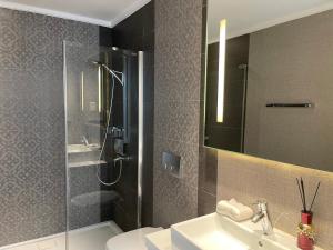 a bathroom with a shower and a sink and a mirror at Olympic Residence Deluxe Apartments in Limassol