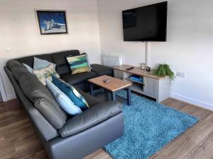 a living room with a leather couch and a table at Caledonia Place in Aviemore