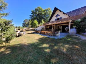 a house with a yard with tables and chairs at Stacaravan 6 persoons - Camping Le Soustran in Neuvic