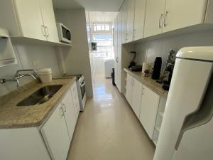 una cocina con armarios blancos y fregadero. en Duas suítes Leblon a duas quadras da praia, en Río de Janeiro