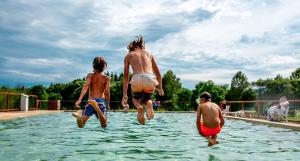 a group of people jumping into a swimming pool at CampHouse in Chvalšiny