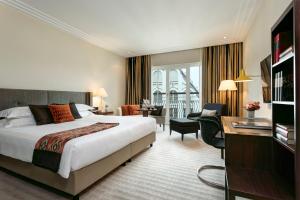 a hotel room with a large bed and a large window at Rocco Forte The Charles Hotel in Munich