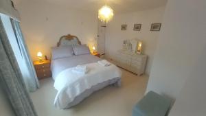 a white bedroom with a white bed and two lights at Quayside in Porthscatho