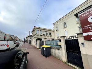 een straat met auto's aan de zijkant van een gebouw bij Logement très cosy en plein centre-ville in Saint-Cyr-lʼÉcole