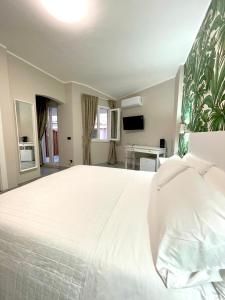 a bedroom with a large white bed and a television at ALDIVA ROOMS in Torvaianica