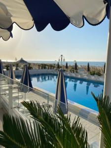 利多迪迪耶索洛的住宿－安東尼酒店，一个带遮阳伞和椅子的游泳池以及大海