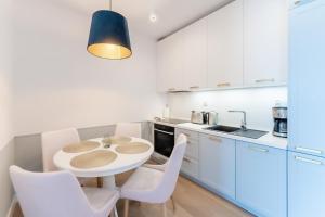 kuchnia z białymi szafkami, stołem i krzesłami w obiekcie Aqua Polanki Apartament B014 Eltom Tour w Kołobrzegu