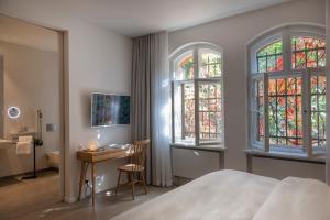 a bedroom with a bed and two windows and a desk at Wilmina Hotel in Berlin