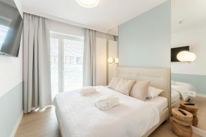sypialnia z białym łóżkiem i ręcznikami na nim w obiekcie Aqua Polanki Apartament B014 Eltom Tour w Kołobrzegu +16 zdjęć