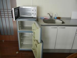 una pequeña cocina con microondas y nevera vacía en Villa May Queen, en Fujikawaguchiko