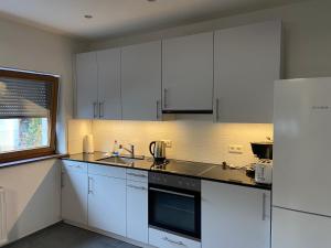 een keuken met witte kasten, een wastafel en een koelkast bij Gemütliche Ferienwohnung EVIELINE in Todtnau in Todtnau