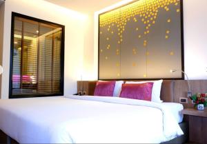 una camera con un letto bianco e un grande dipinto sul muro di The Beach Heights Condotel Kata 500 meters to Kata beach a Kata Beach