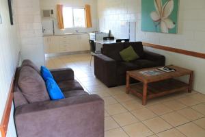 a living room with two couches and a coffee table at Oasis Inn Apartments in Cairns