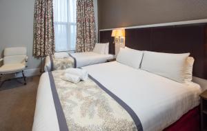a hotel room with two beds and a chair at Best Western Chiswick Palace & Suites London in London