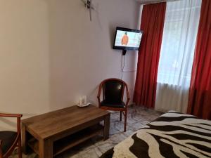 a room with a table and a tv and a chair at Motel “La Butuci” in Timisul de Jos